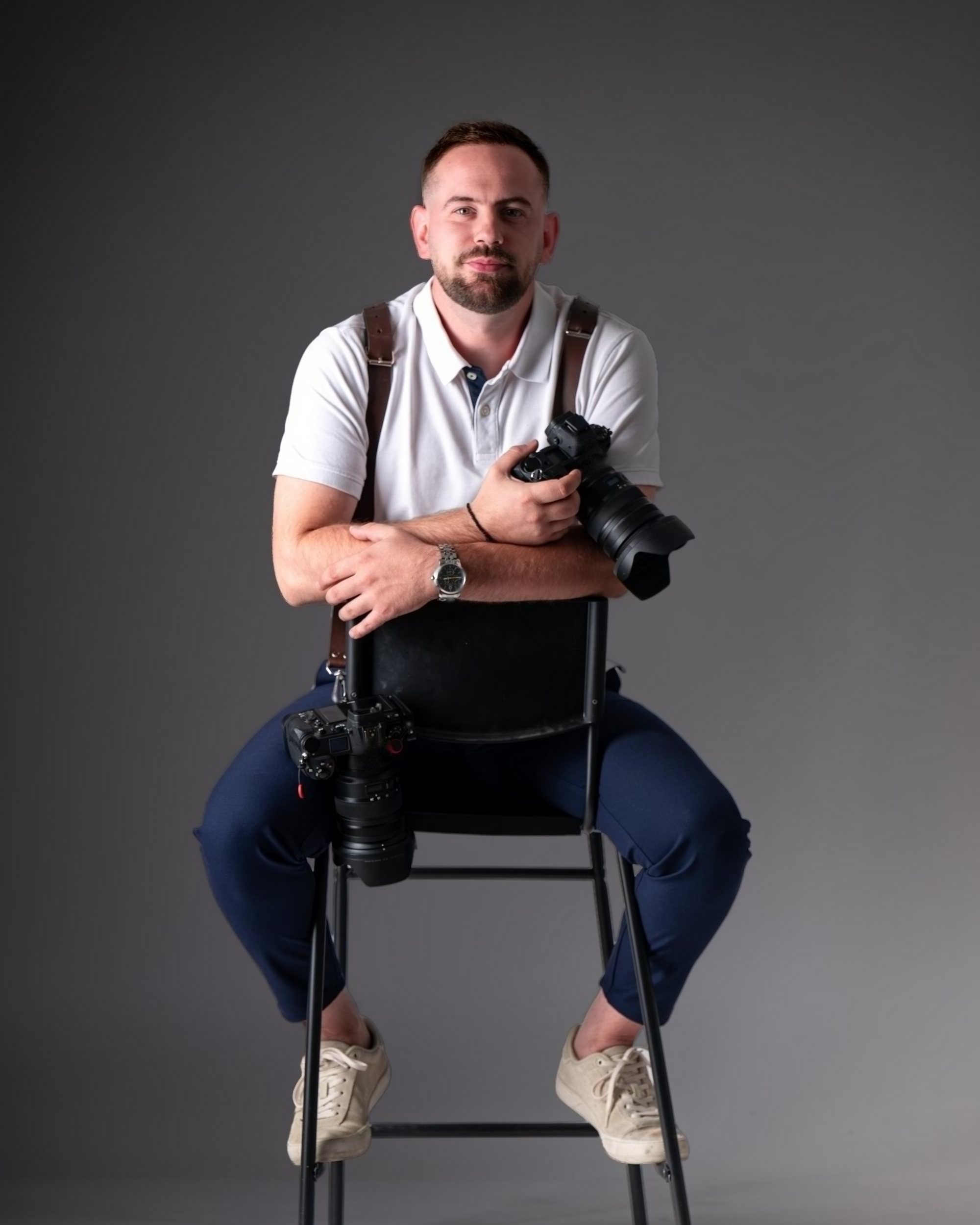 Daniel Vulic mit zwei Kameras auf einem Hocker im Fotostudio