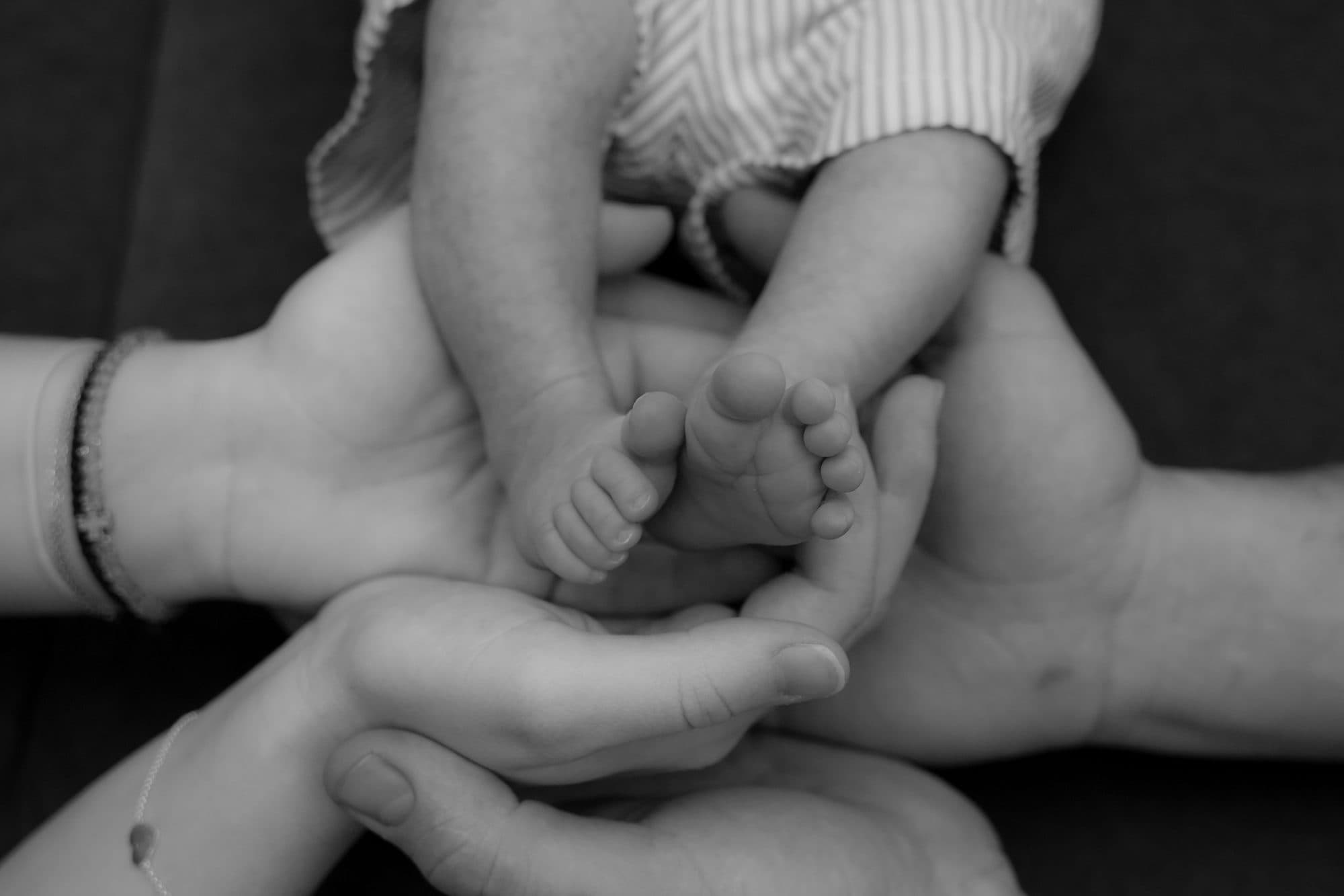 Babyfüßchen in den Händen der Eltern, schwarz-weiß
