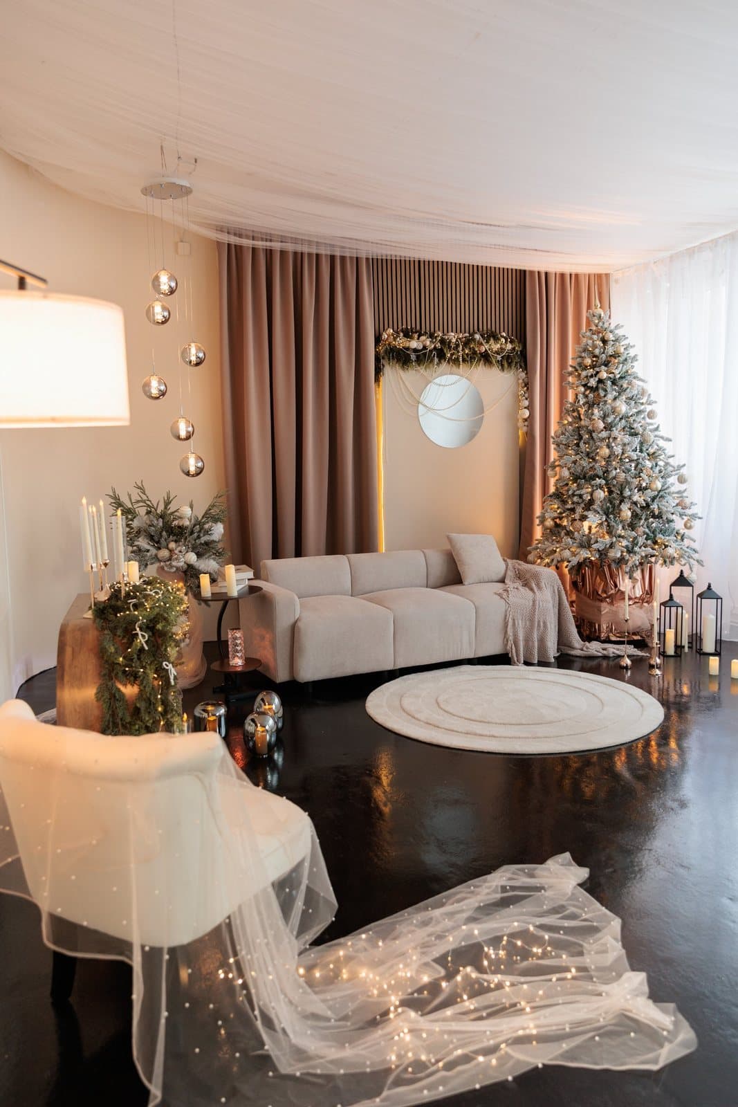 Das weihnachtliche Studio in Linz mit Sofa, Baum, rundem Teppich und Schleier mit Lichterkette